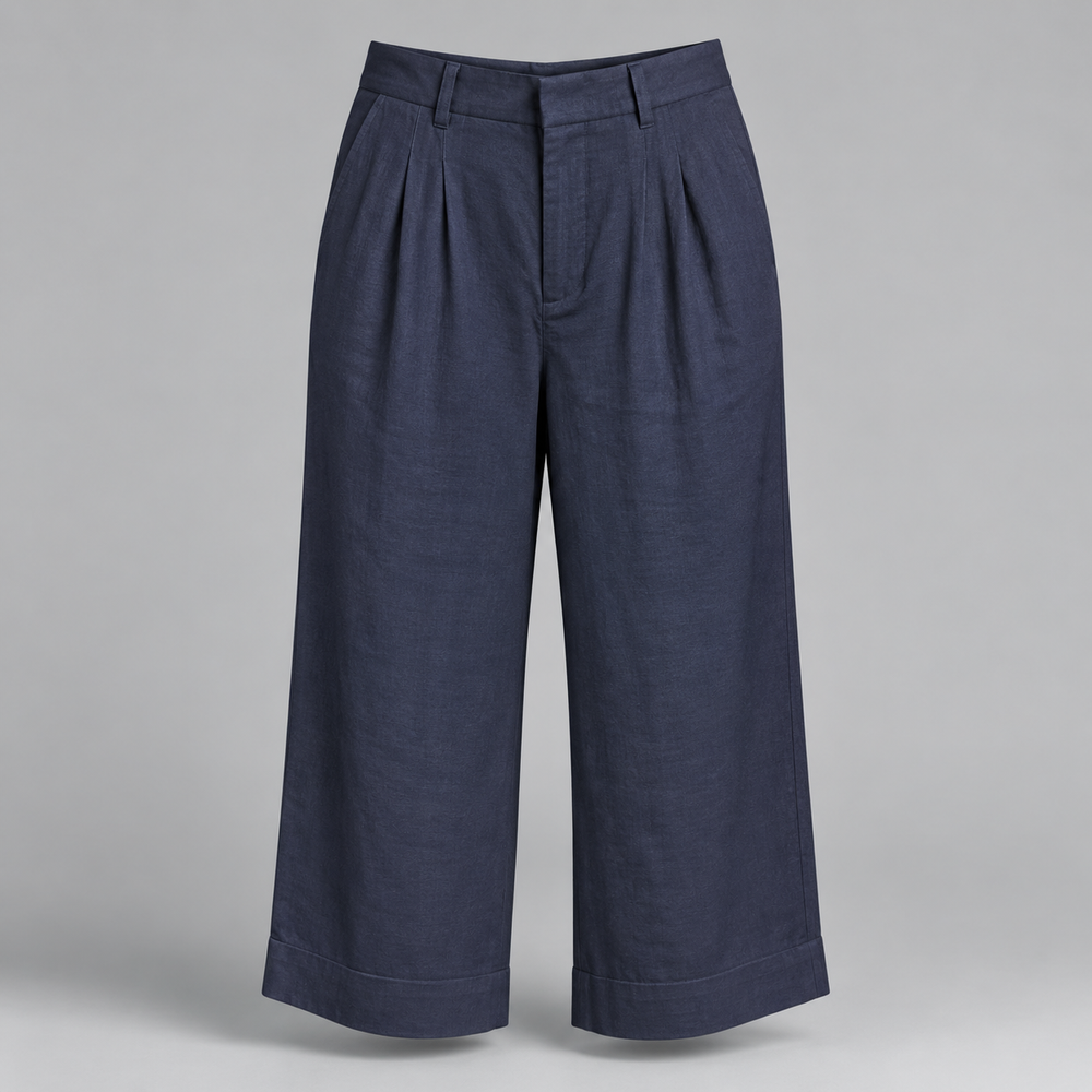 A pair of dark navy blue cropped trousers with pleated front details and wide legs, displayed on a neutral gray background.