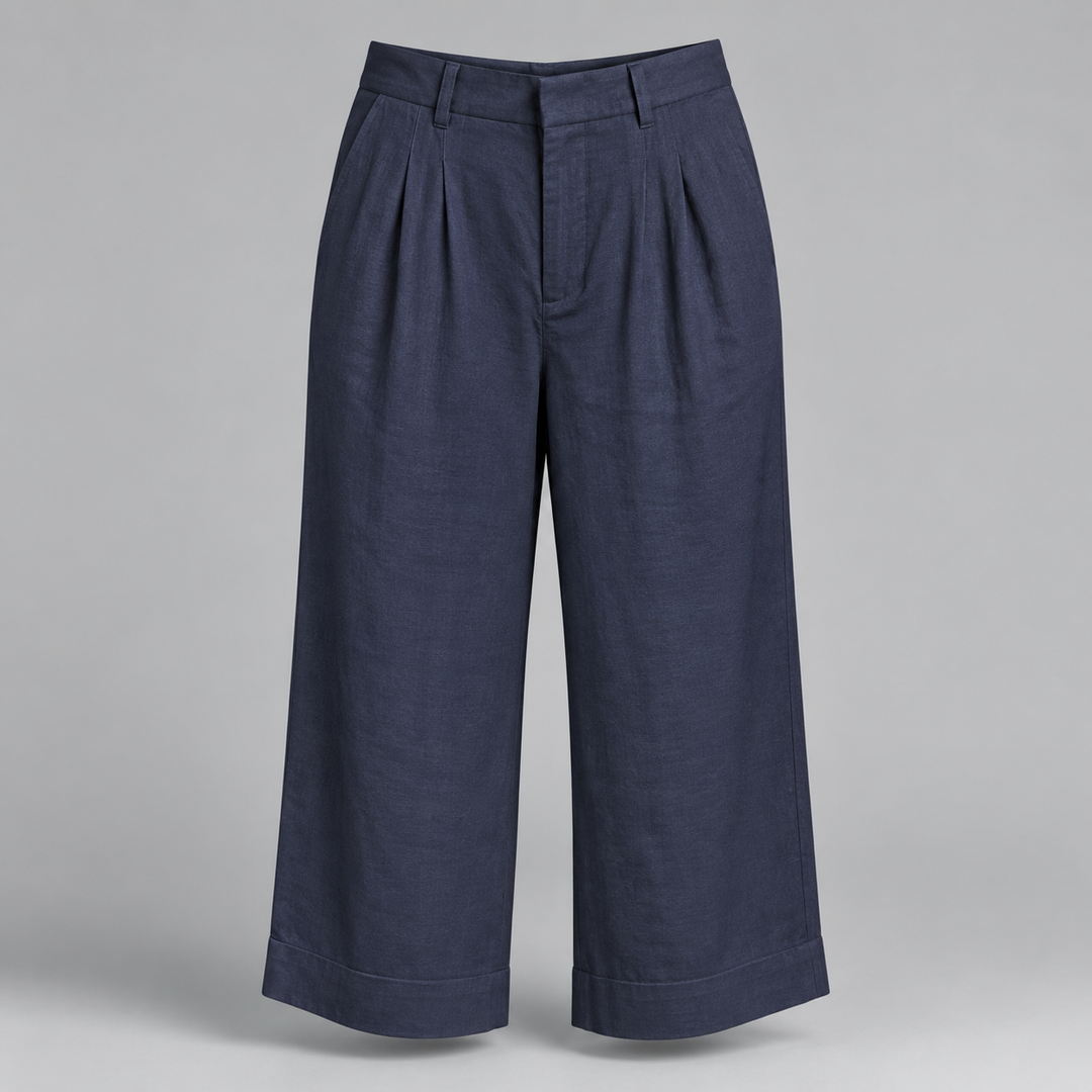 A pair of dark navy blue cropped trousers with pleated front details and wide legs, displayed on a neutral gray background.