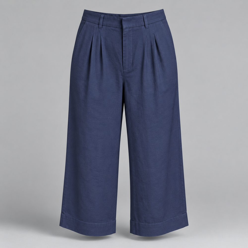 A pair of navy blue cropped trousers with pleated front details and rolled cuffs, displayed on a neutral gray background.