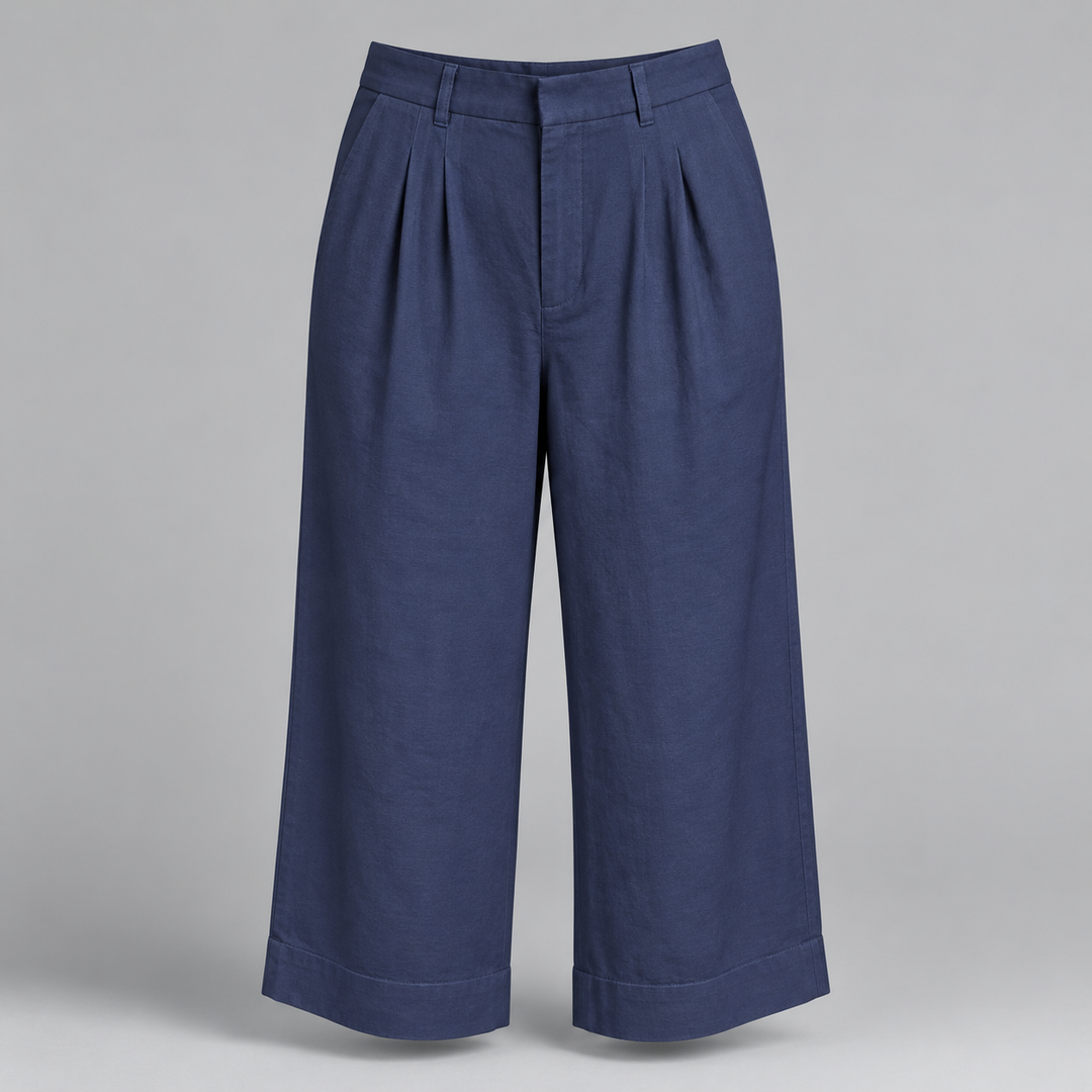 A pair of navy blue cropped trousers with pleated front details and rolled cuffs, displayed on a neutral gray background.
